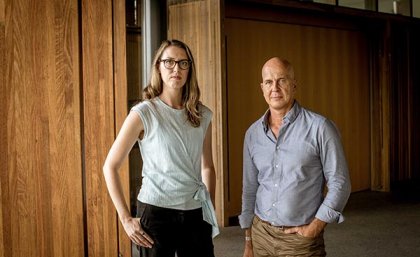 Rebecca Ananian-Welsh and Peter Greste standing next to each other in a large lobby with wooden panelling 